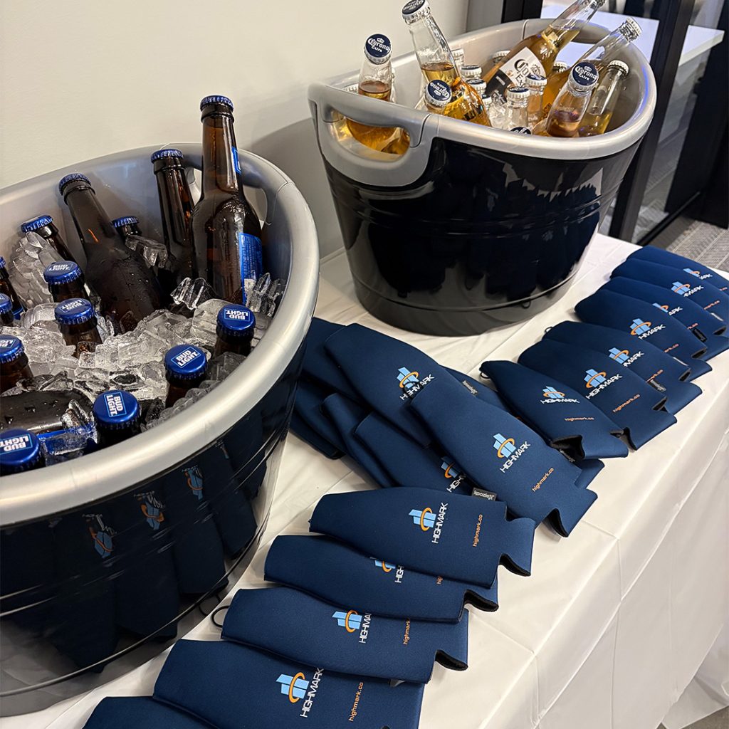 Two large coolers filled with ice and bottled beer for a promotional event, with navy branded napkins laid out nearby.